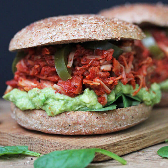 Jackfruit BBQ burger med guacamole, jalapenos og spinat på en fjøl.