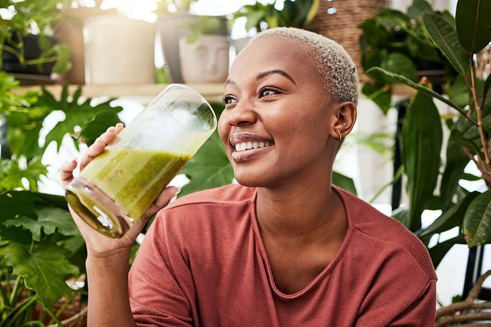 En afroamerikansk dame drikker grønn smoothie