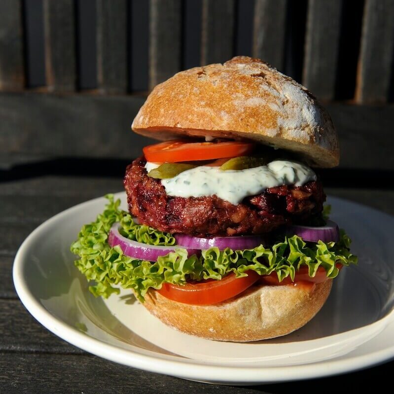 En saftig rødbetburger mellom med frisk salat, rødløk, tomat og dressing.