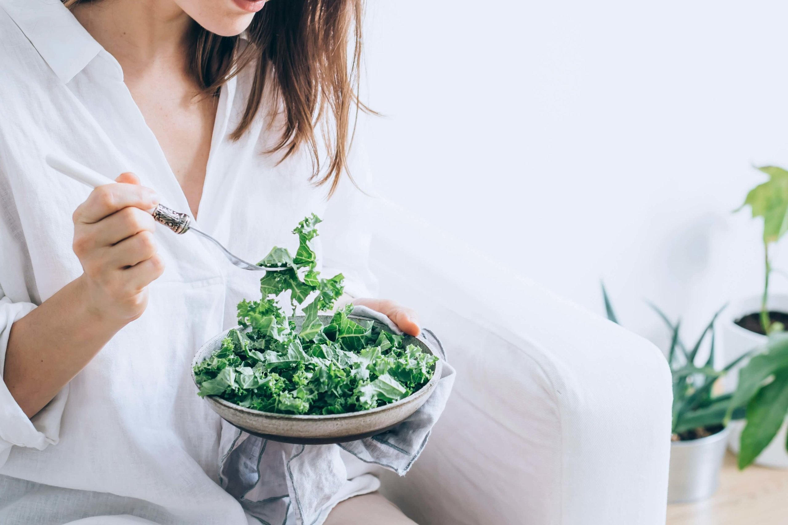 En kvinne sitter og spiser en stor grønn salat