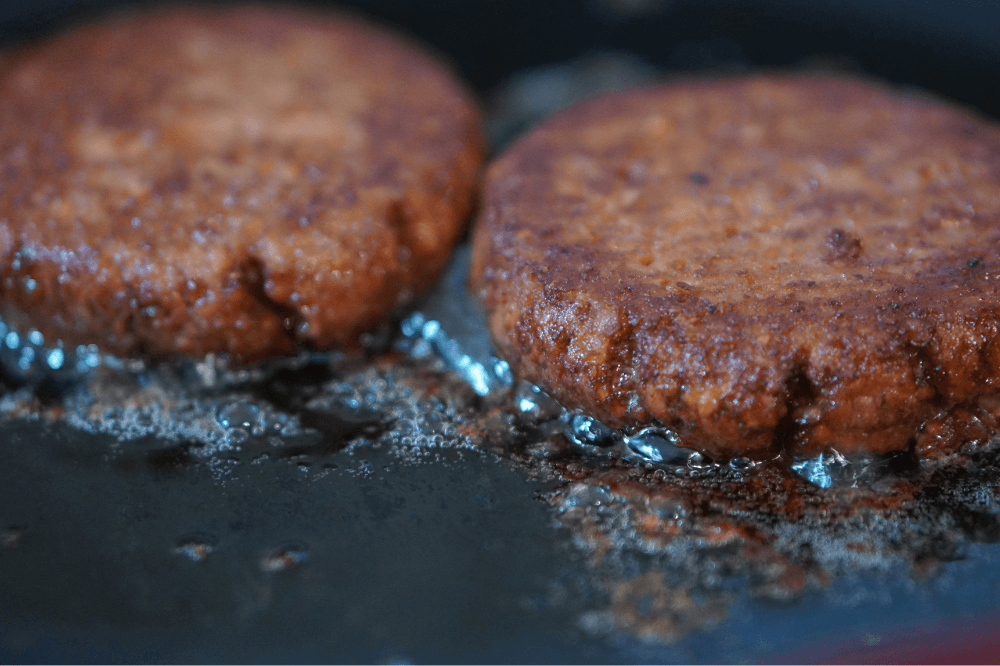 To veganske burgere laget av erteprotein freser i en stekepanne