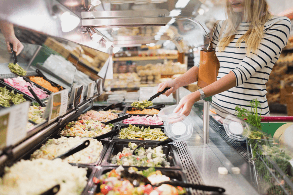 Anonym kvinne skal til å lage seg en salat i en salatbar