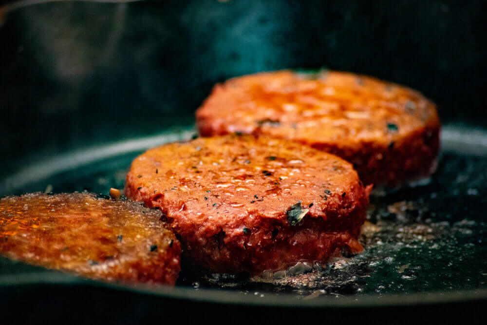 tre veganske burgere stekes i panne