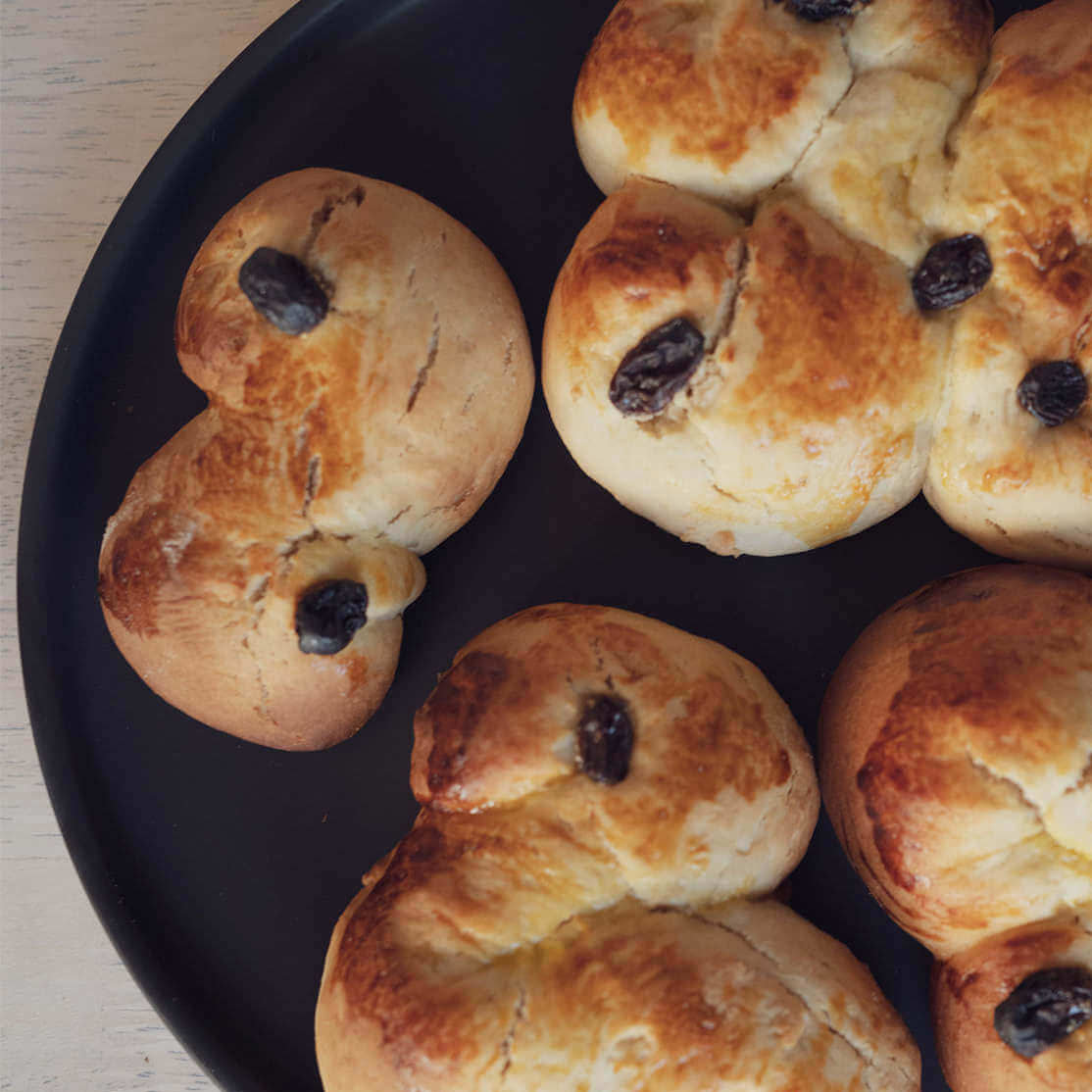 En tallerken med luftige, veganske lussekatter, pyntet med rosiner.