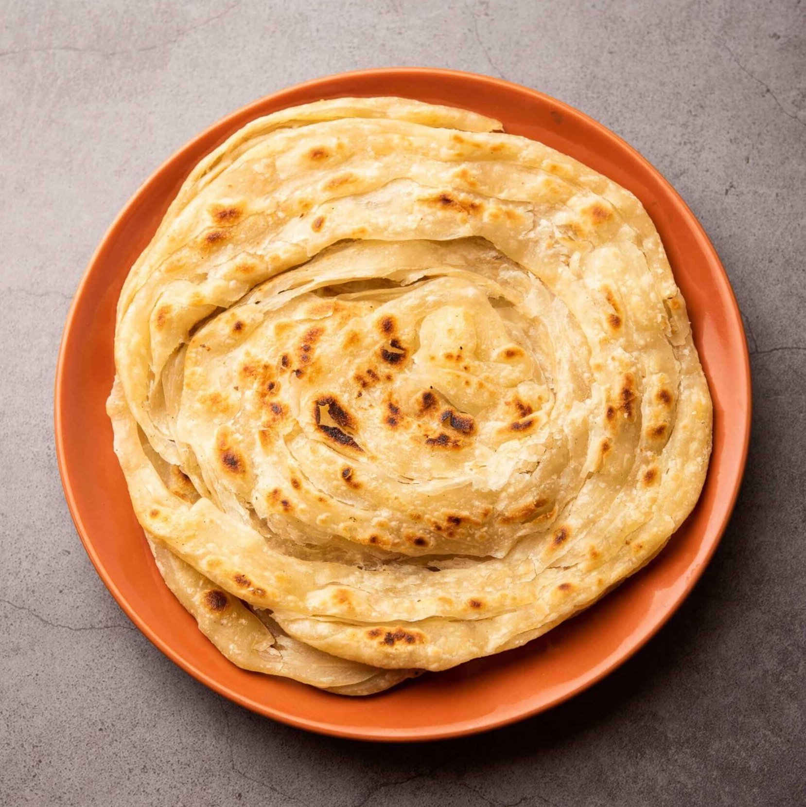 Et nystekt paratha-brød på en oransje tallerken.