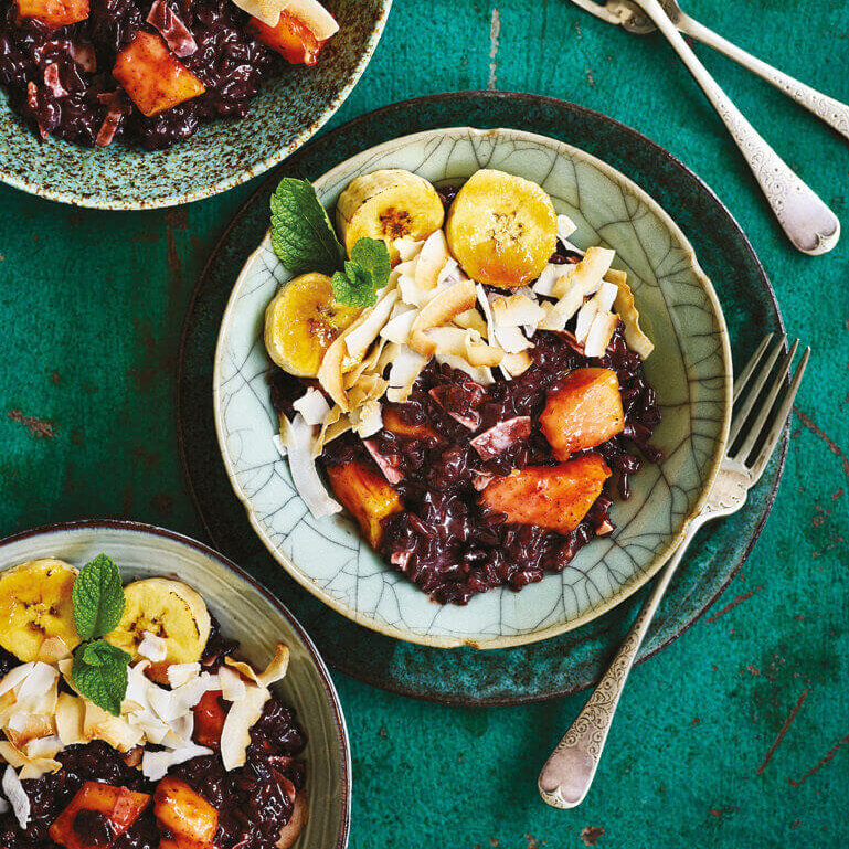 En skål med black sticky rice pudding, toppet med fersk frukt.