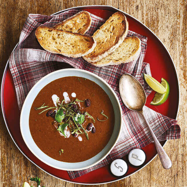 En skål med rykende fersk, svart bønnesuppe med nyristet brød som tilbehør.