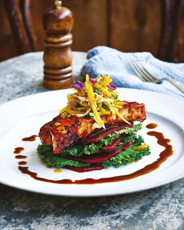 barbecue-tempeh på toppen av rødbedskiver, toppet med ovnsbakt flaskegresskar.