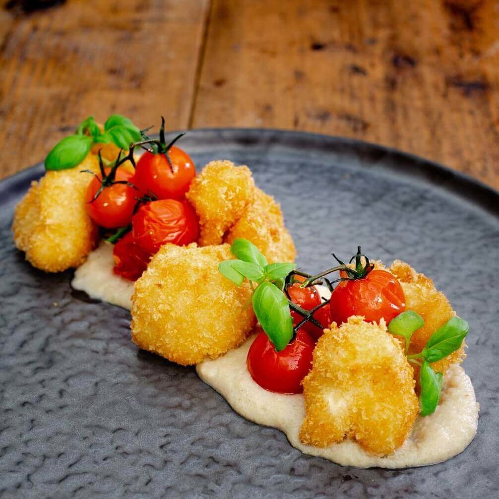 En ru tallerken panerte blomkål med blomkålsaus og ovnsbakte cherrytomater.