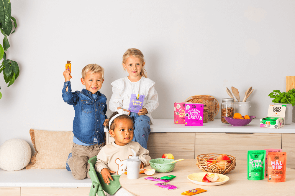 Tre barn som holder fargerike GroGro-produkter.