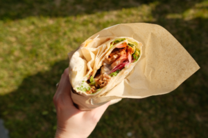 Hånd holder vegansk kebab fra two monkeys.