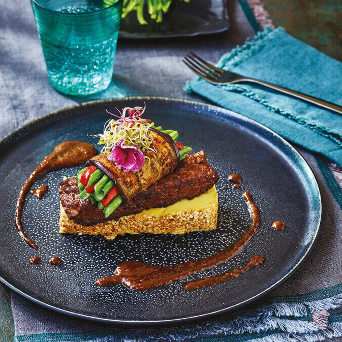 En imponerende forrett med tofu og grønnsaker på en stor kermaikktallerken.