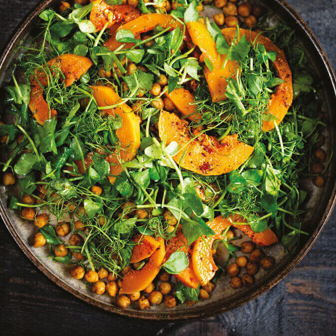En stor keramikkbolle med en fargesterk salatblanding i grønn og oransje.
