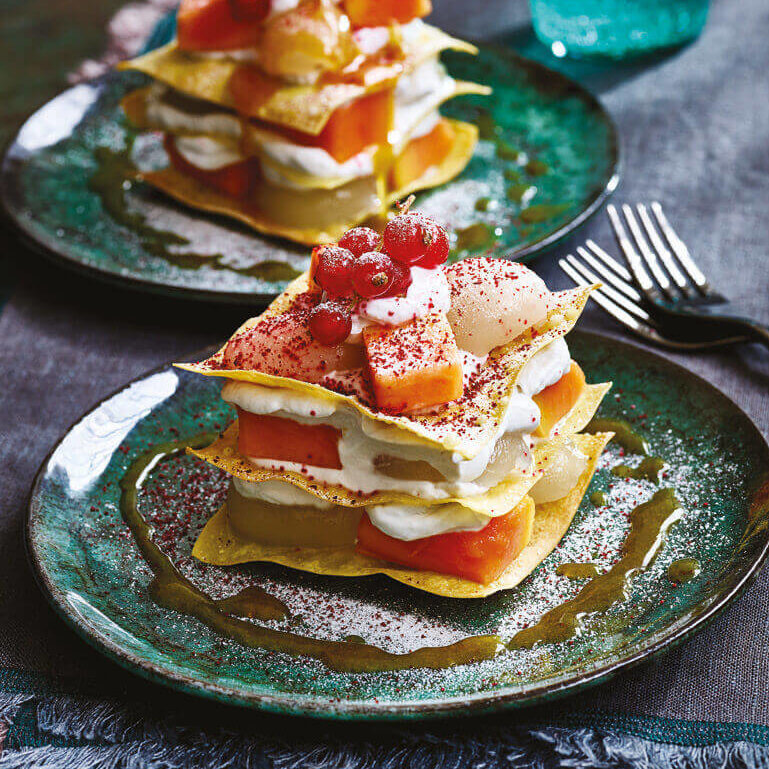 Elegant mille-feuille dessert på en tallerken med saus og et dryss melis på kanten.