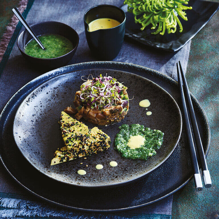 En asjett med posjert tofu, auberginetilbehør og galangalsaus.