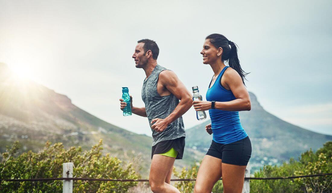 Ungt par jogger sammen ute i naturen.