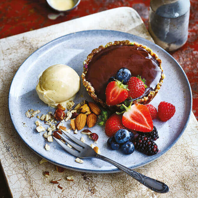 En stor tallerken med sjokoladeganache, friske bær og vegansk vaniljeis.
