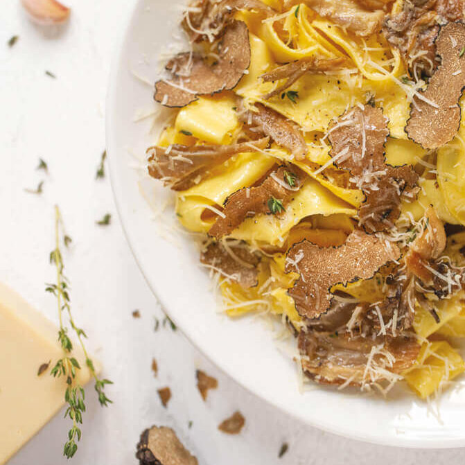 Hjemmelaget pasta med tynne skiver trøffel og et dryss vegansk parmesan.