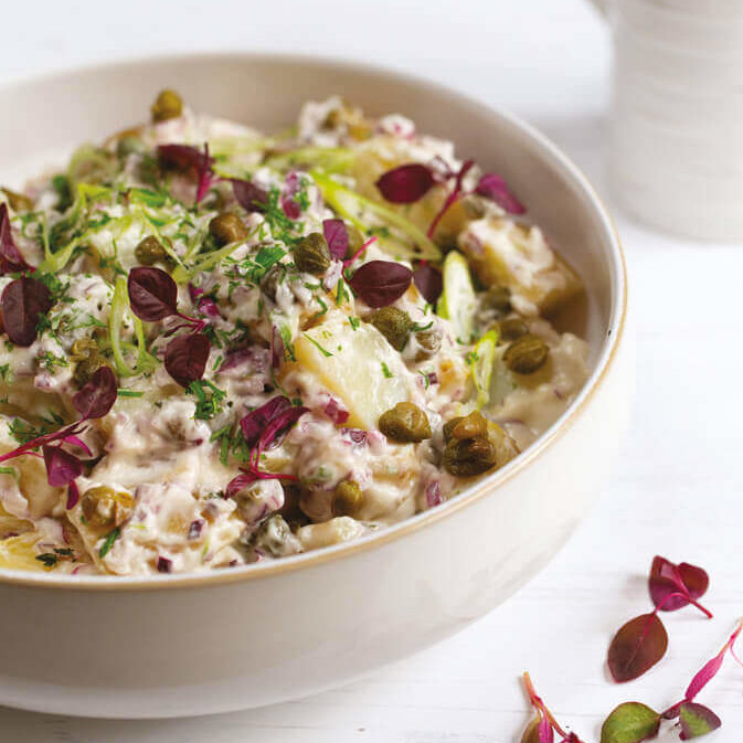 En skål kremete, vegansk potetsalat med kapers.