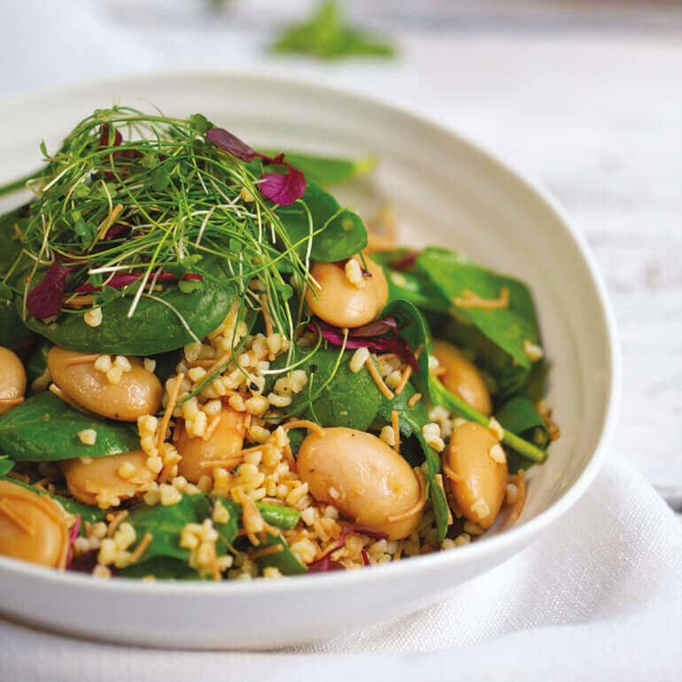 en liten bolle med grønn spinatsalat, store bønner, bokhvete og tynne biter av vermicelli-pasta.