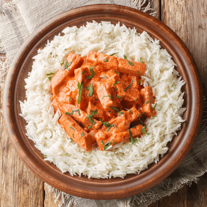 Lun pølsestroganoff servert over ris, pyntet med persilleblader.