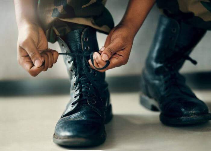 Nærbilde av soldat som knyter skolisser på uniformsstøvler.
