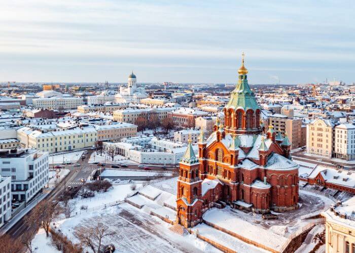 Bybilde av Helsinki, FInland, med en storslagen kirke i murstein i forgrunnen.