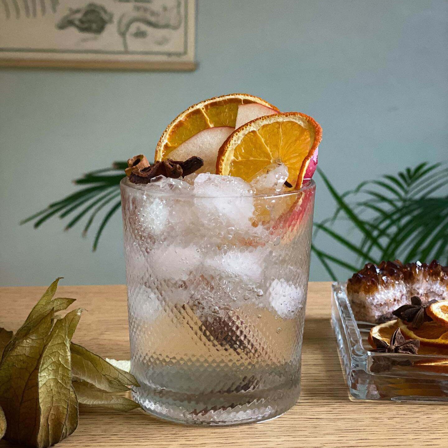 Et glass gin&tonic pyntet med appelsinskiver og barnåler.