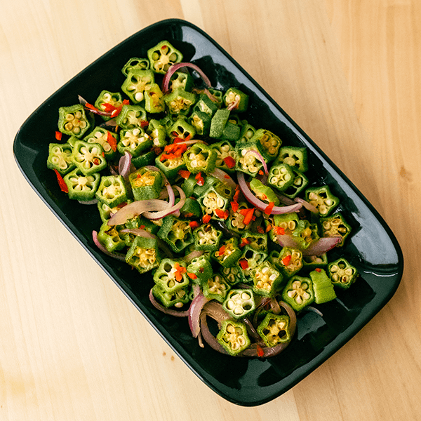 Nystekt og velduftende okra på en avlang, svart tallerken.