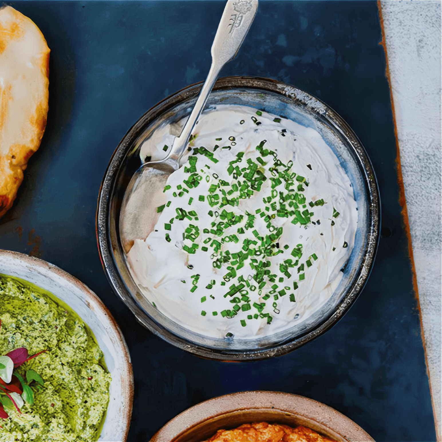 Kremete vegansk hvitløksrømmedipp toppet med gressløk i en skål.